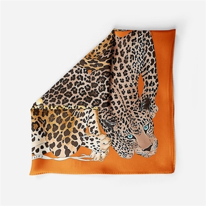Detailed macro shot of luxury orange silk square scarf with artistic leopard print design