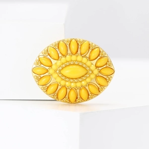 Macro detail of golden sunflower brooch with yellow gemstone on a white geometric stand