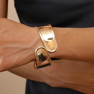 Detailed view of wide gold crossover cuff bracelet with high-polish mirror finish