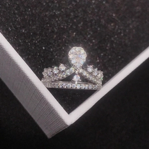 Close-up of crown ring with pear-cut main stone and pavé setting in a black gift box