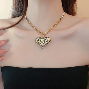 Close-up of a heart pendant necklace with leopard print on a gold chunky metal chain