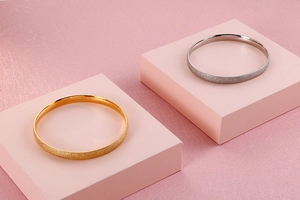 Close-up of minimalist gold and silver titanium bracelets with matte frosted texture