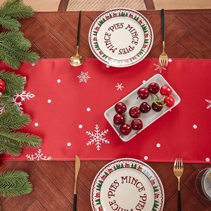 Christmas table runner with red linen print and white snowflakes on wooden table