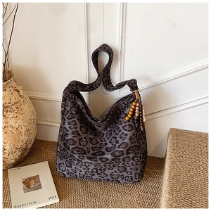 Detailed view of leopard print hobo bag with wood bead tassel and soft fabric texture