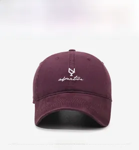 Detail of burgundy cotton baseball cap with white adventure embroidery on the front