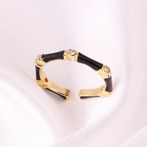 Detail of gold bamboo ring with black enamel sections and three clear zircon stones