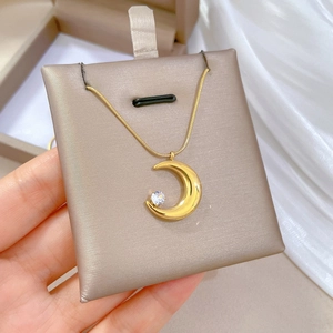 Macro detail of gold moon pendant necklace with zircon on elegant snake chain