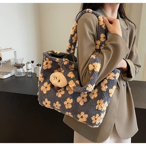 Detail of plush floral tote bag with a soft fuzzy charm on a cafe-themed background