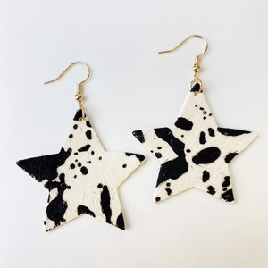 Détail macro de boucles d'oreilles en cuir en forme d'étoile avec motif vache et crochets dorés