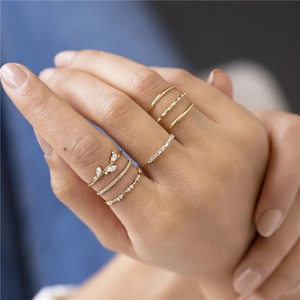 Detail of stacked gold rings featuring sparkling crystals and leaf design on model finger