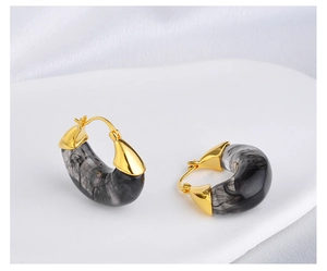 Detail of moon-shaped marble resin earrings with elegant golden metal tips and hooks