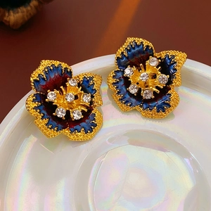 Macro view of vintage floral earrings with blue enamel petals and sparkling crystal center