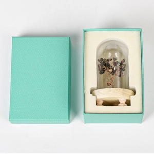 Crystal tree with gemstone leaves in glass dome inside a blue gift box on wood base