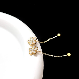 Detail of elegant gold flower drop earrings with white petals and fine tassel chains