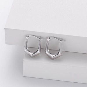 Macro shot of silver geometric U-shaped earrings displayed on a white tiered stand