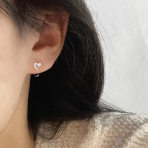 Close-up of a minimalist hollow heart silver earring worn on a woman's earlobe