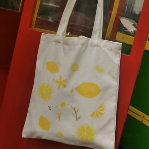 Close-up of white canvas tote bag with vibrant yellow lemon and floral pattern print