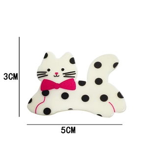 Detail view of a 5x3cm white cat hair clip with black polka dots and pink bow