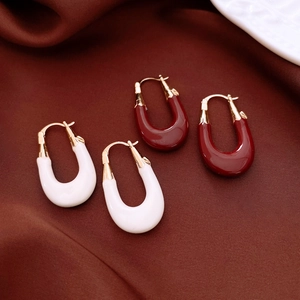 Detailed view of U-shaped earrings in red and white with gold plated metal accents