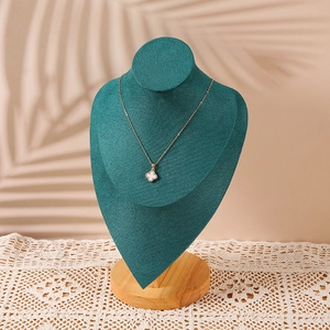 Golden clover necklace with white inlay on dark green velvet bust and wooden base