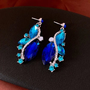 Macro detail of teardrop earrings with blue crystals and rhinestones on black display