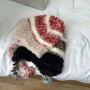 Detail of colorful knitted winter hat with earflaps and fringe on white background