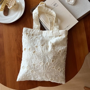 Close-up of white lace floral embroidery and hollow-out craft on cotton tote bag