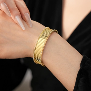 Vue détaillée d'un bracelet doré strié serti de cristaux pavés sur le poignet d'un mannequin