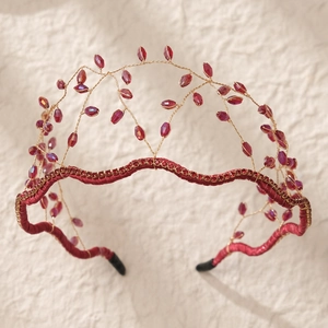 Detailed view of red crystal beads and gold wire mesh on a handmade crown headband
