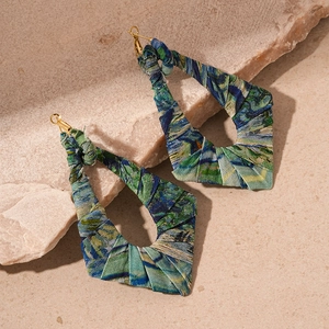 Dettaglio di orecchini geometrici bohémien avvolti in tessuto batik verde-blu con gancio oro