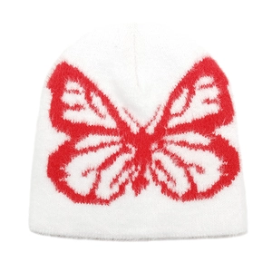 Close-up of white plush knit beanie featuring a red butterfly jacquard pattern
