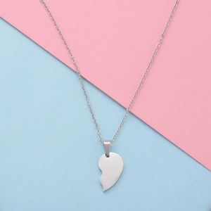 Macro detail of silver half-heart pendant with polished mirror finish and cable chain