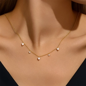 Close-up of a minimalist gold S925 silver necklace with five small heart pendants on a model