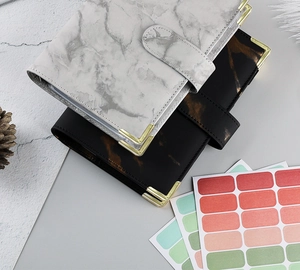 Flat lay of marble texture PU leather A6 binders with gold metal corners and colorful stickers