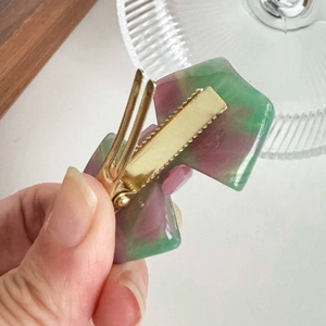 Green and purple acetate bow hair clip with a watercolor effect and gold duckbill clip