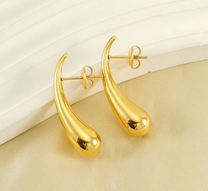 Detailed close-up of golden teardrop earrings on elegant silk background fabric