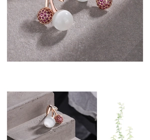 Macro shot of rose gold cherry stud earrings with white cat-eye stone and pink zircon