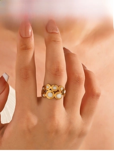 Detail of overlapping gold circles ring with white enamel inlay worn on finger