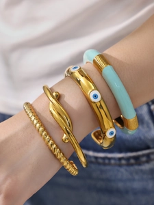 Primo piano di quattro bracciali in acciaio inossidabile dorato e smalto indossati da un modello
