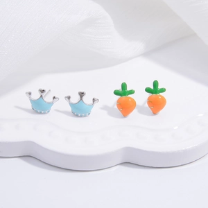 Macro view of S925 silver stud earrings featuring blue crown and orange carrot shapes