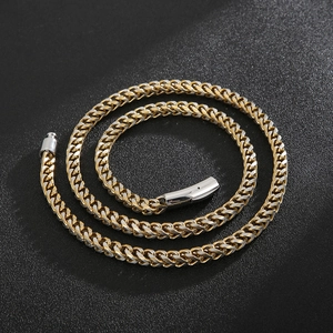Detailed view of bicolor woven chain necklace with cylindrical clasp on black surface