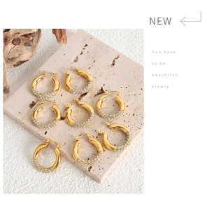 Macro detail of gold hoop earrings with sparkling rhinestones on minimalist stone pedestal