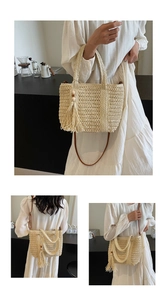 Close-up of beige woven straw tote bag featuring decorative tassels and dual top handles