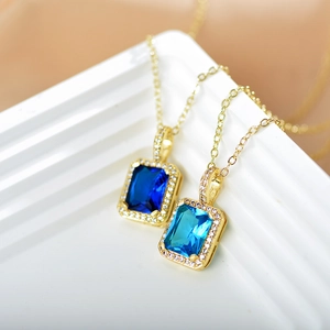 Close-up of golden necklaces featuring rectangular blue sapphire stones and zircon borders
