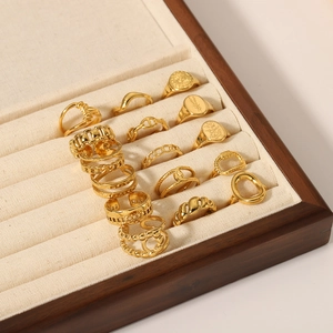 Minimalist gold rings set with woven knot and geometric textures in a jewelry box