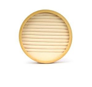 Close-up of a round bamboo jewelry tray with beige velvet slots for rings and earrings