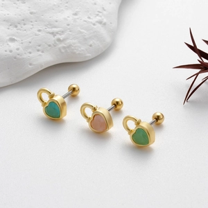 Boucles d'oreilles cartilage coeur doré avec pierres roses et vertes sur fond blanc