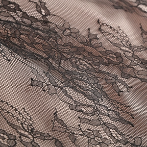 Detail von aufwendigem schwarzen Blumen-Spitzenstoff mit feiner Netzstruktur am Kleid