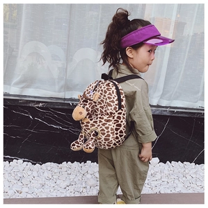 Detail of cute plush giraffe kids backpack featuring 3D ears and horns on a child model