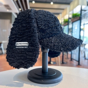 Dettaglio del cappello con paraorecchie in peluche nero e toppa con logo MS:FRCCDOM